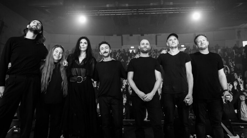 A photo of the members of the band Maybeshewill, plus string players Sophie Green and Alex Williams standing on with the audience behind them.